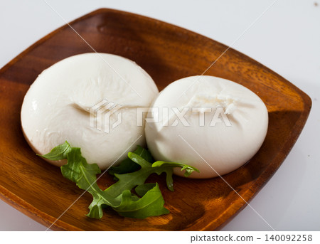 Burrata italian cheese and arugula green leaf at wooden plate Burrata italian cheese and arugula green leaf at wooden plate 140092258