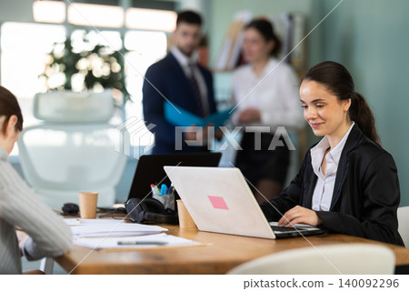 Young woman works on laptop with colleagues Young woman works on laptop with colleagues 140092296