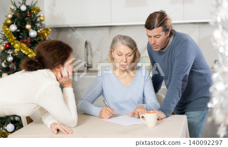 Man and woman help elderly mother make will and fill out document correctly On Christmas Eve Man and woman help elderly mother make will and fill out document correctly On Christmas Eve 140092297
