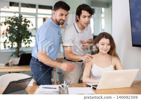 Colleagues discussing project on laptop of man Colleagues discussing project on laptop of man 140092309