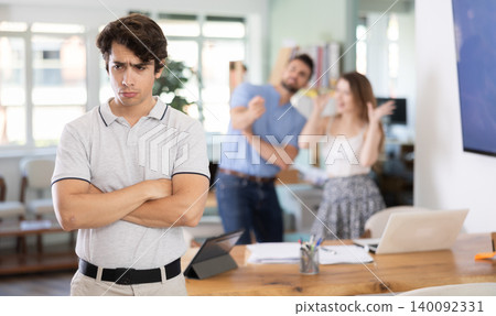 Oppressed male office employee is ridiculed, reproached, and humiliated by colleagues 140092331