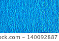 Real swimming pool water photograph featuring bright sunlight reflections, blue tiles, and dynamic ripple patterns. 140092887