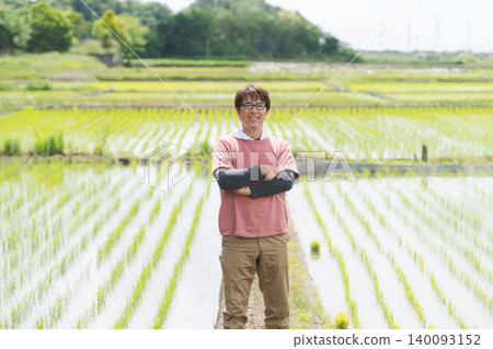 A rice farmer standing on the embankment of a rice paddy. 140093152