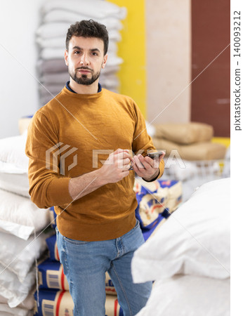 Young man using smartphone in grocery warehouse Young man using smartphone in grocery warehouse 140093212