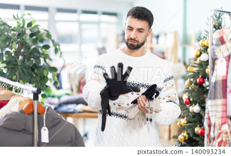 Man choose and try on gloves in store, X mas shopping Man choose and try on gloves in store, X mas shopping 140093234