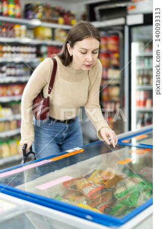 Woman spends time in store, looking for necessary goods and get out from refrigerator Woman spends time in store, looking for necessary goods and get out from refrigerator 140093313