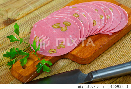 Sliced cooked mortadella sausage stuffed with olives 140093333