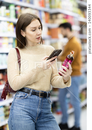 Woman get acquainted with good, scan QR code, take reading label using phone camera in shop Woman get acquainted with good, scan QR code, take reading label using phone camera in shop 140093344