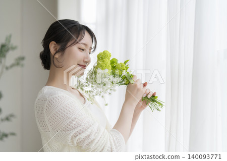 A woman in her 30s holding flowers (profile view) A woman in her 30s holding flowers (profile view) 140093771