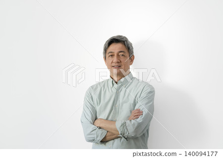 一位六十多歲的男子雙手交叉抱在胸前,面帶微笑,直視鏡頭。 一位六十多歲的男子雙手交叉抱在胸前,面帶微笑,直視鏡頭。 140094177