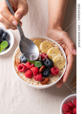 Oatmeal breakfast bowl with raspberry, blueberry, banana and almond ready to eating, Top view Oatmeal breakfast bowl with raspberry, blueberry, banana and almond ready to eating, Top view 140094386