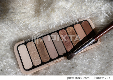 Nude eyeshadow palette with multiple shimmer and matte shades, presenting a range of warm and neutral tones for versatile everyday beauty looks, resting on a soft white background Nude eyeshadow palette with multiple shimmer and matte shades, presenting a range of warm and neutral tones for versatile everyday beauty looks, resting on a soft white background 140094723