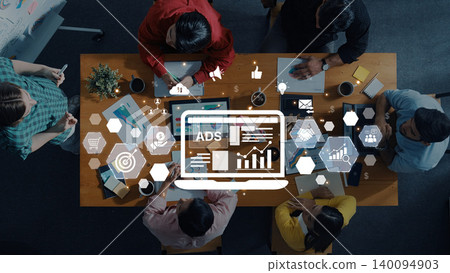 Group of Diverse People Collaborating on Digital Ads Strategy with Infographics and Data Visualization Elements in Modern Workspace Environment Trope 140094903