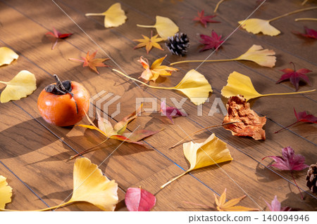 Scattered red maple leaves, ginkgo leaves, pine cones, and persimmons – an image of autumn. Scattered red maple leaves, ginkgo leaves, pine cones, and persimmons – an image of autumn. 140094946