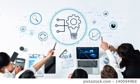 Business team collaborating on creative strategy with charts, graphs, technology, and innovative ideas represented by a light bulb and gear on desk Trope 140094968
