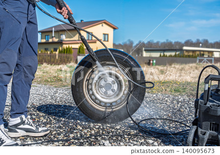 Car tire cleaning with high pressure washer outdoors, auto detailing and maintenance concept 140095673