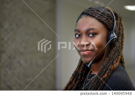 Portrait of a young Black female customer service representative wearing a headset in a modern office Portrait of a young Black female customer service representative wearing a headset in a modern office 140095948