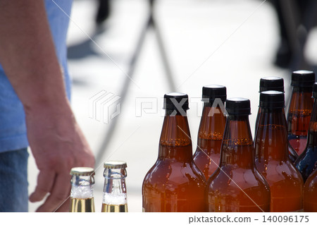 Brown Beer Bottles On Outdoor Market Table With Customer Hand Reaching For Bottle 140096175