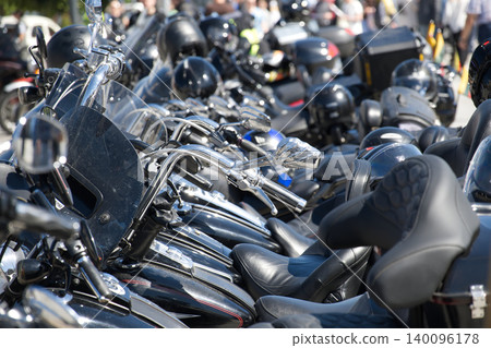 Row of Parked Motorcycles and Helmets at a Busy Bike Rally With Gleaming Chrome Row of Parked Motorcycles and Helmets at a Busy Bike Rally With Gleaming Chrome 140096178