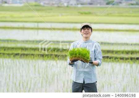 一位農夫手持水稻秧苗 140096198