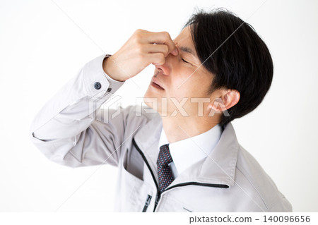 身穿灰色工作服的中年商人,因眼睛疲勞而顯得神情恍惚,背景為白色。 身穿灰色工作服的中年商人,因眼睛疲勞而顯得神情恍惚,背景為白色。 140096656