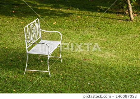 Vintage white metal garden chair on a lush green lawn in a peaceful backyard garden 140097058