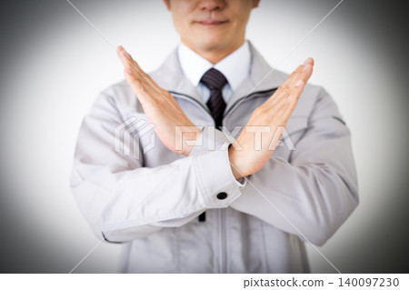 一位身穿灰色工作服的中年商人在白色背景前用手比劃了一個「X」形手勢。 一位身穿灰色工作服的中年商人在白色背景前用手比劃了一個「X」形手勢。 140097230