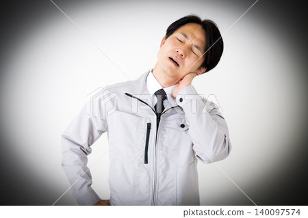 身穿灰色工作服的中年商人,面露疲憊之色,背景為白色。 身穿灰色工作服的中年商人,面露疲憊之色,背景為白色。 140097574