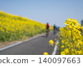 A spring cycling path and cyclists seen through rapeseed blossoms. 140097663