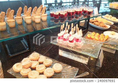 A wide variety of sweets are lined up at the buffet. A wide variety of sweets are lined up at the buffet. 140097691