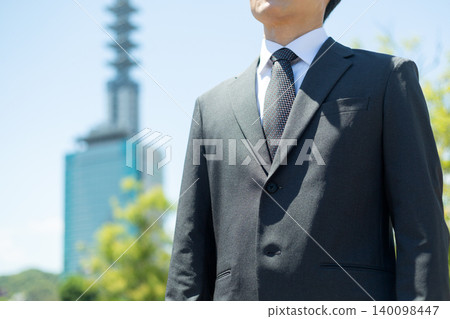 一位身穿西裝的中年商人站在辦公區戶外。 140098447