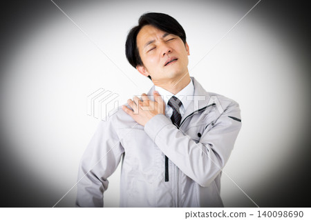 A middle-aged businessman in gray work clothes suffering from stiff shoulders, against a white background. A middle-aged businessman in gray work clothes suffering from stiff shoulders, against a white background. 140098690