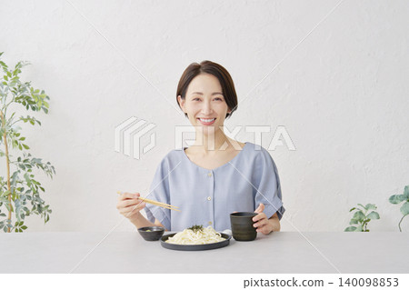 A woman eating Zaru Udon noodles in the living room A woman eating Zaru Udon noodles in the living room 140098853
