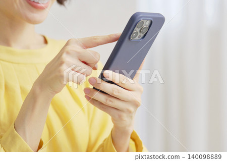 A woman who uses a smartphone in the living room without a face A woman who uses a smartphone in the living room without a face 140098889