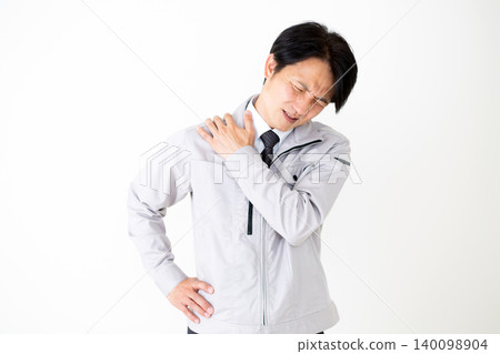 一位身穿灰色工作服的中年商人,肩膀僵硬,背景為白色。 一位身穿灰色工作服的中年商人,肩膀僵硬,背景為白色。 140098904