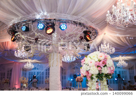 Elegant banquet hall decorated for wedding with chandeliers and floral arrangements 140099066
