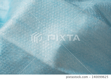 Texture of a blue non-woven surgical mask with wrinkles and undulations; macro photography background. 140099625