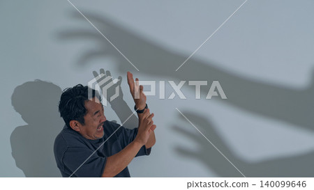 A man is terrified by the shadow of a monster. 140099646