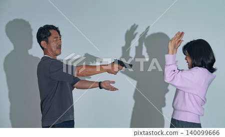 A man points a gun at a woman. A man points a gun at a woman. 140099666