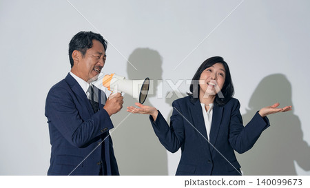 A male businessperson uses a megaphone to scold a woman. 140099673
