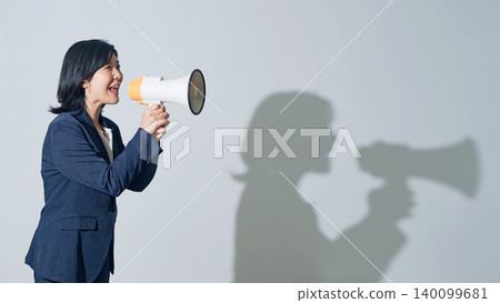 一位女女商人對著擴音器大聲喊叫。 一位女女商人對著擴音器大聲喊叫。 140099681