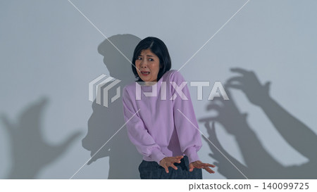 A woman terrified by the shadow of a monster A woman terrified by the shadow of a monster 140099725