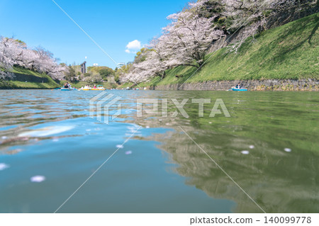 A clear blue sky and the cherry blossom trees lining Chidorigafuchi, with a lively scene of people enjoying cherry blossom viewing from boats on the water. A clear blue sky and the cherry blossom trees lining Chidorigafuchi, with a lively scene of people enjoying cherry blossom viewing from boats on the water. 140099778
