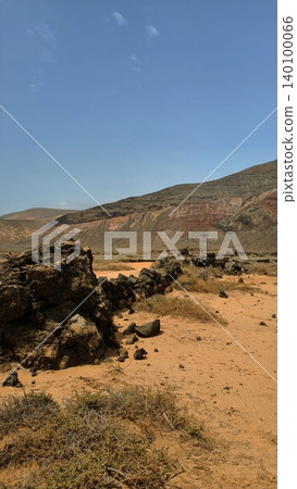 Wide view of Lanzarote desert landscape with volcanic hills and stark island beauty Wide view of Lanzarote desert landscape with volcanic hills and stark island beauty 140100066