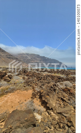 Wide view of Lanzarote desert landscape with volcanic hills and stark island beauty Wide view of Lanzarote desert landscape with volcanic hills and stark island beauty 140100073