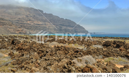 Wide view of Lanzarote desert landscape with volcanic hills and stark island beauty Wide view of Lanzarote desert landscape with volcanic hills and stark island beauty 140100076