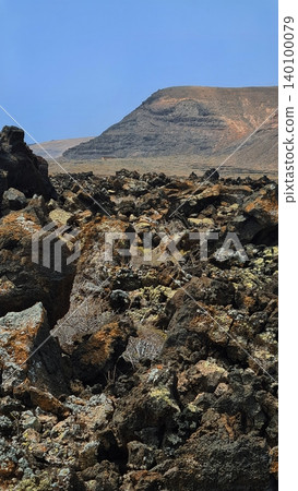 Wide view of Lanzarote desert landscape with volcanic hills and stark island beauty Wide view of Lanzarote desert landscape with volcanic hills and stark island beauty 140100079
