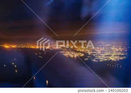The window of a passenger plane flying from Haneda Airport to Naha. A view of Japan's nightscape from 10,000 meters above ground. Tokyo International Airport, Ota Ward, Tokyo. The window of a passenger plane flying from Haneda Airport to Naha. A view of Japan's nightscape from 10,000 meters above ground. Tokyo International Airport, Ota Ward, Tokyo. 140100203