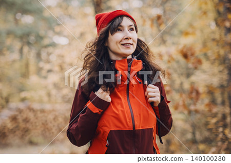 Smiling woman walks through autumn forest with stack of timber logs in background. responsible nature tourism, low impact recreation, ecological footprint awareness. 140100280