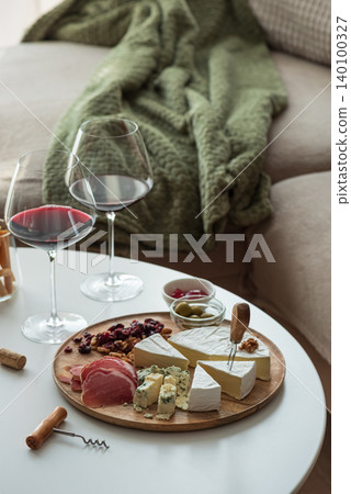 Cozy living room with two glasses of red wine and cheese on table Cozy living room with two glasses of red wine and cheese on table 140100327